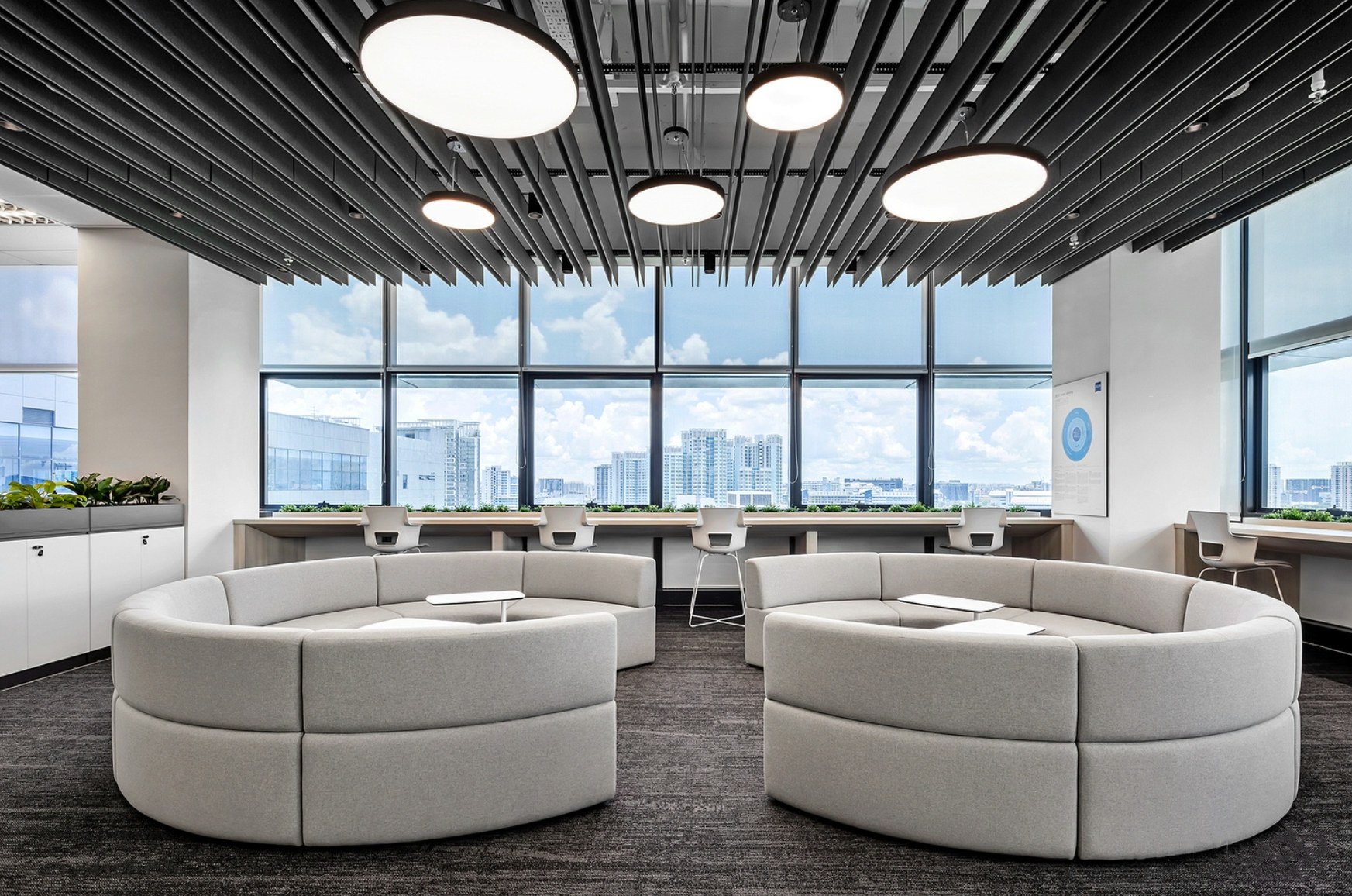 Completed office acoustic ceiling installation with linear black baffles and circular lighting